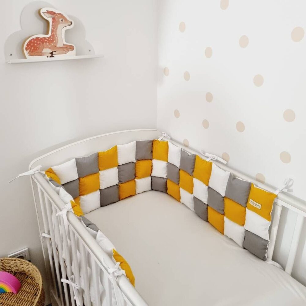 Mustársárga steppelt rácsvédő kiságyban fényképezve