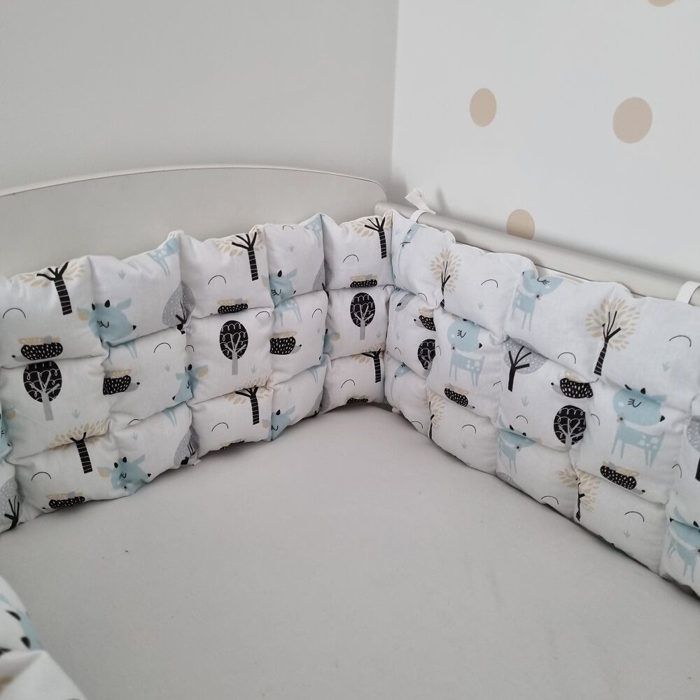 Türkiz őzikés steppelt rácsvédő kiságyban fényképezve