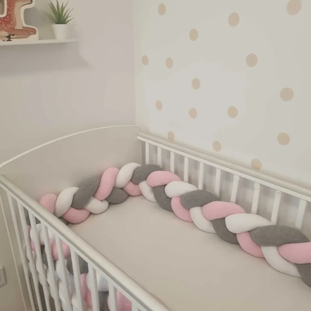 Fonott rácsvédő rózsaszín szürke fehér színben, babyplüss anyagból, kiságyban fényképezve