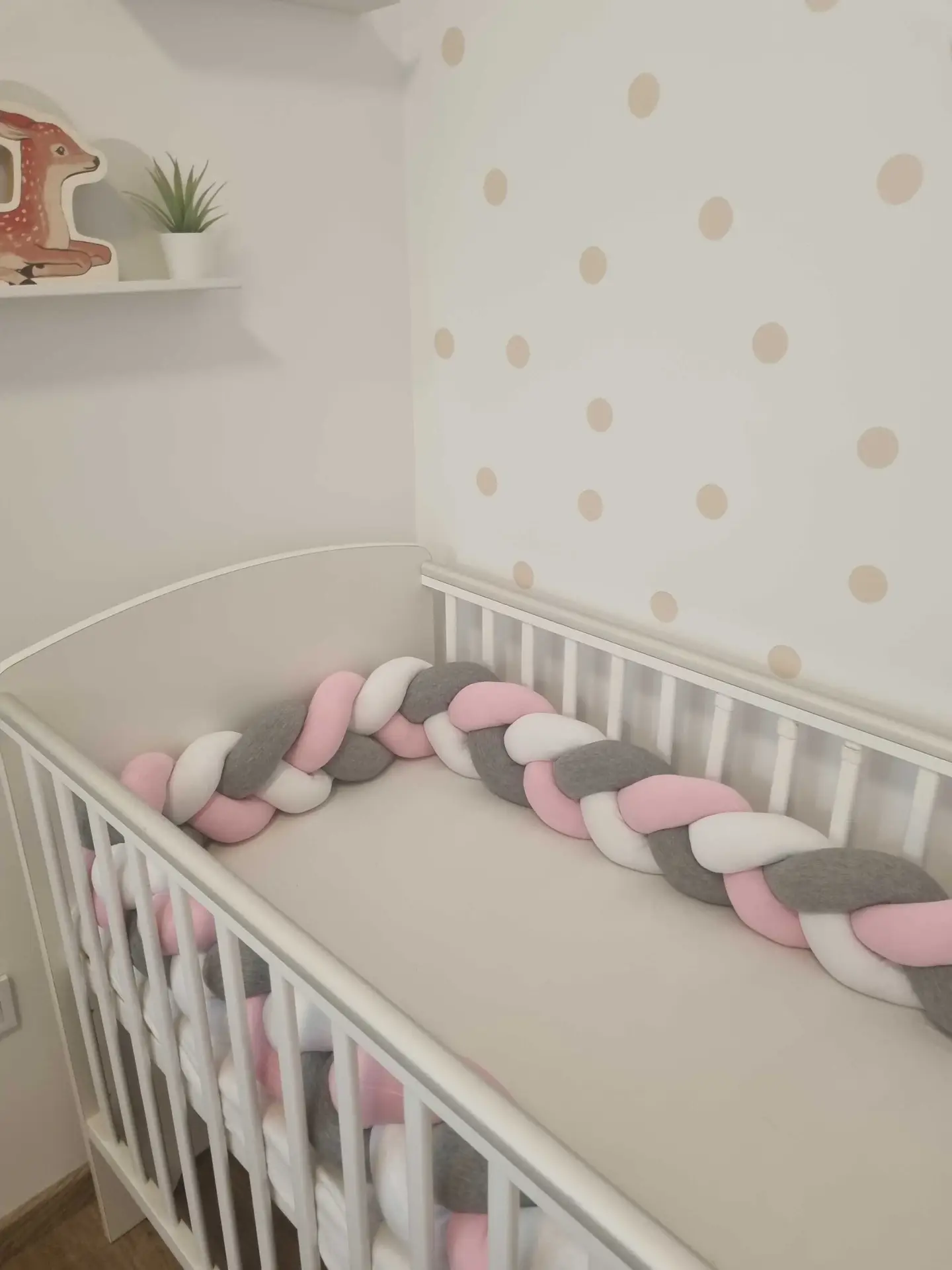 Fonott rácsvédő rózsaszín szürke fehér színben, babyplüss anyagból, kiságyban fényképezve